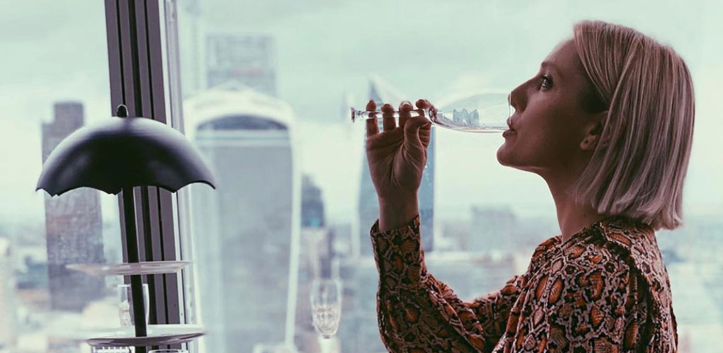 A mature woman drinking champagne while admiring the view at Aqua Shard
