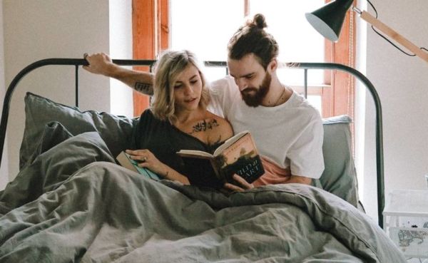 A couple reading a dating book in bed