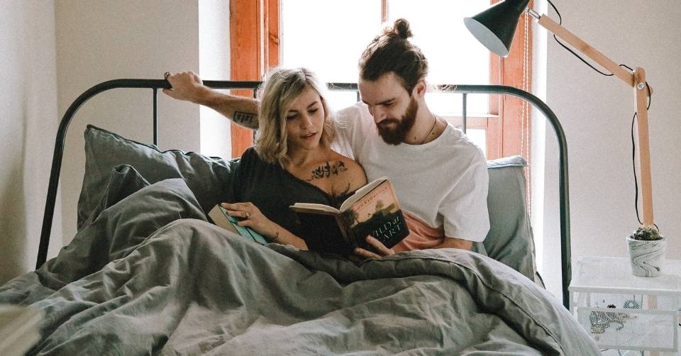 A couple reading a dating book in bed