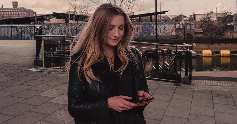 A blonde woman using her phone to try free dating apps