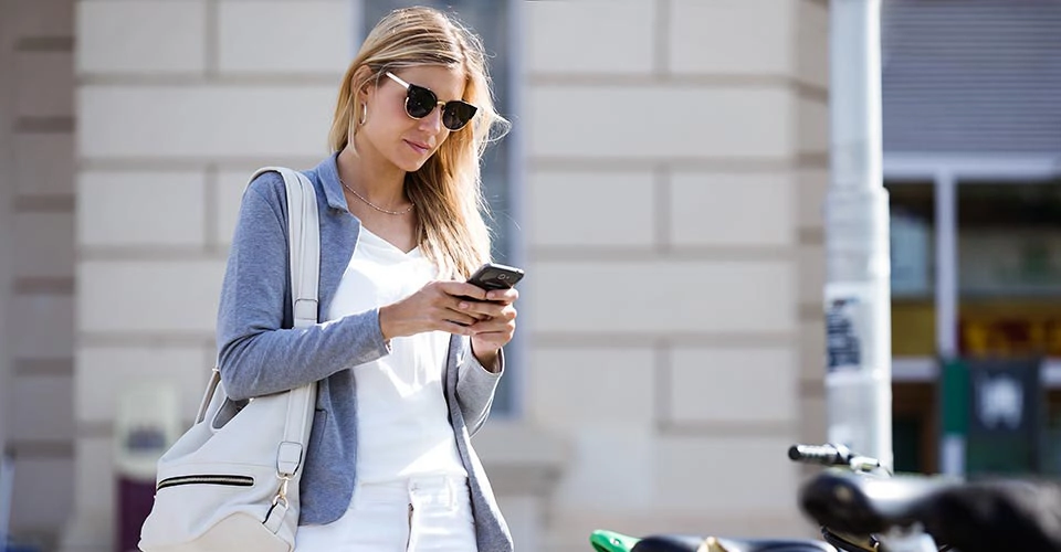 Beautiful young businesswoman texting with her mobile phone whil