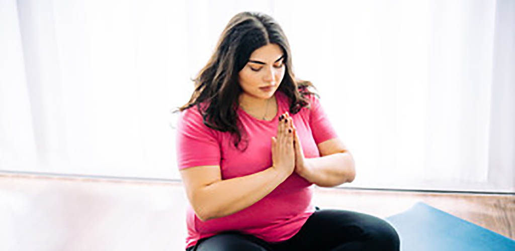 A curvy woman meditating at Lifespan Yoga