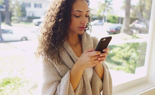 A woman with curly hair trying some Santa Ana dating apps while at home