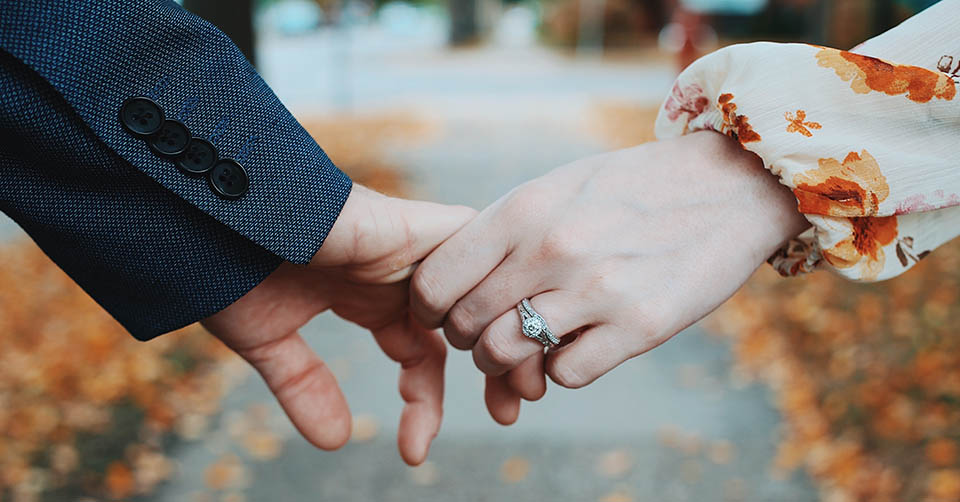 Holding hands while wearing an engagement ring
