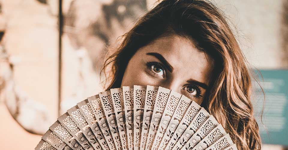 Woman hiding behind a fan