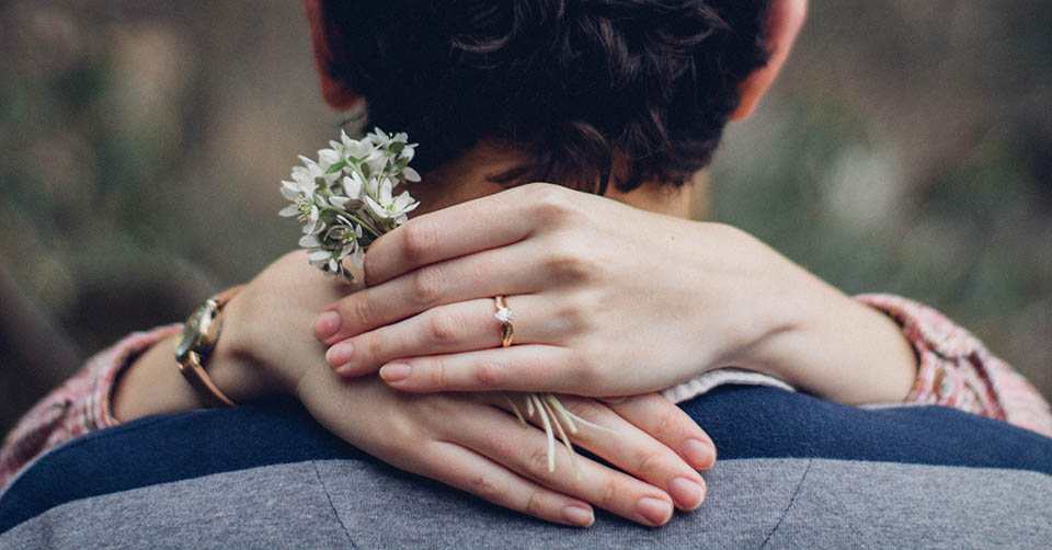 A woman with an engagement ring and a dandelion