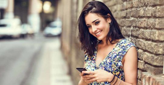 A young woman smiling while using her favorite Colorado dating apps