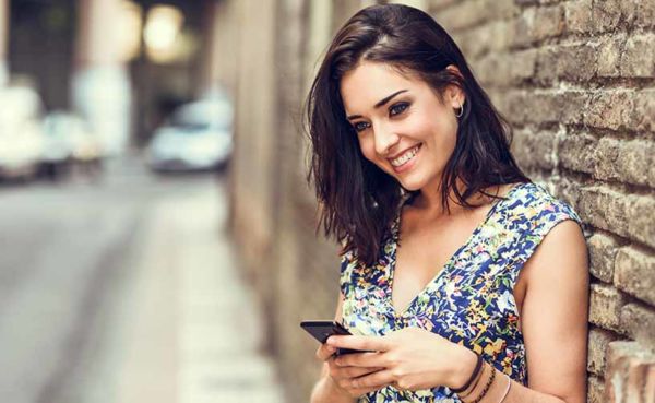 A young woman smiling while using her favorite Colorado dating apps