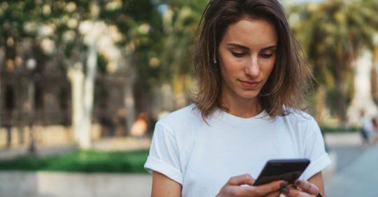 A woman in a white shirt using a South Carolina dating app in the daytime