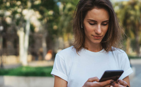 A woman in a white shirt using a South Carolina dating app in the daytime