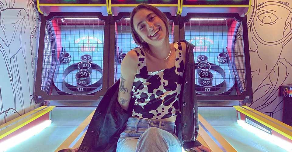 A young woman posing in front of skee ball booths