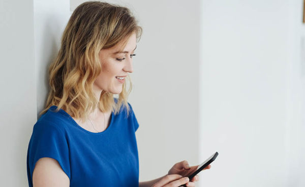 A blonde woman in a blue shirt using a South Dakota dating app at home