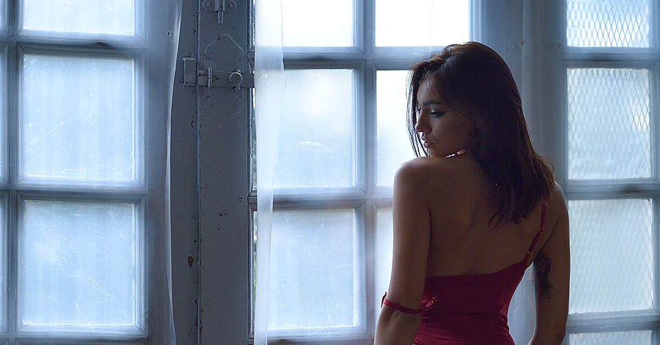 A sexy woman in red lingerie by the window