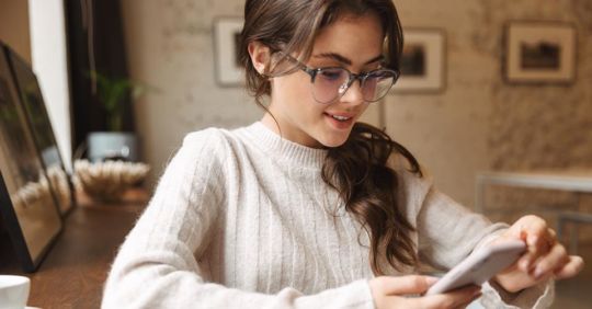 A woman in glasses using an Oregon dating app at home