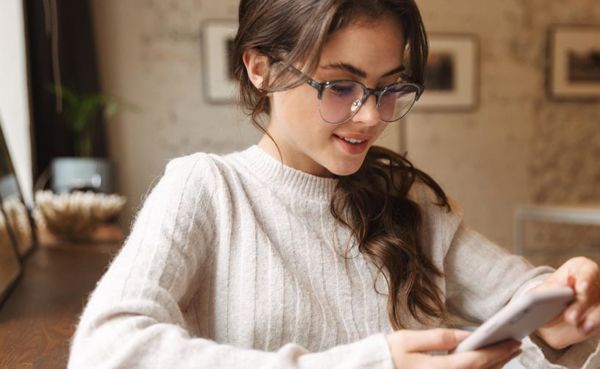 A woman in glasses using an Oregon dating app at home