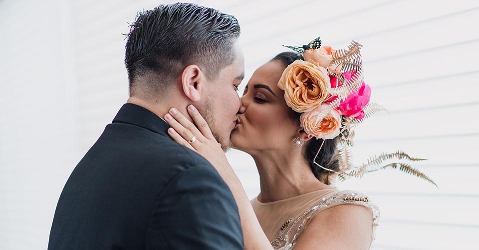 A woman with a colorful headpiece kissing her boyfriend