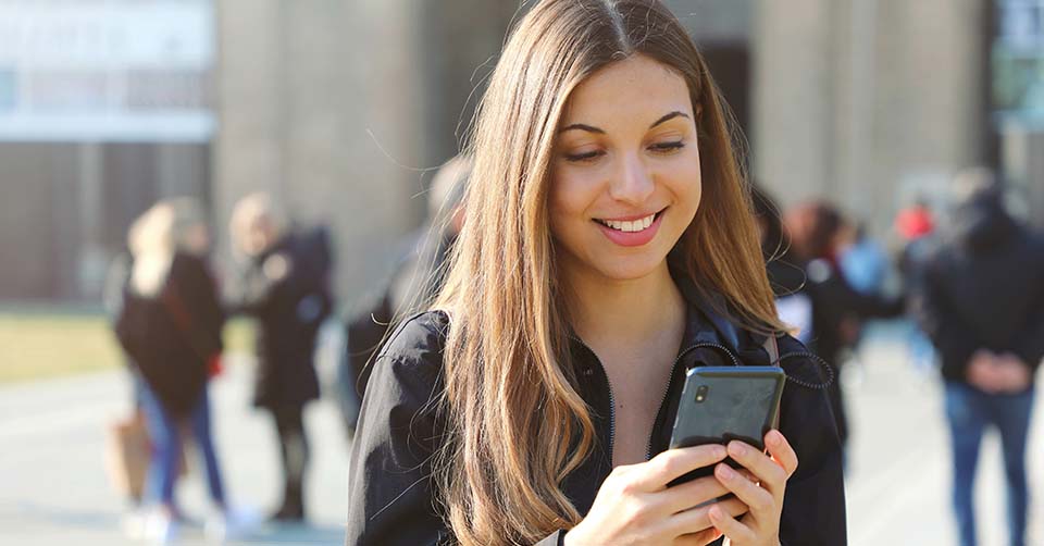A young woman using a Vermont dating app while on her way to class