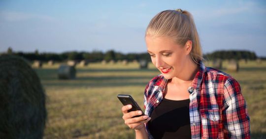 Woman checking out some Wyoming dating apps while in a field