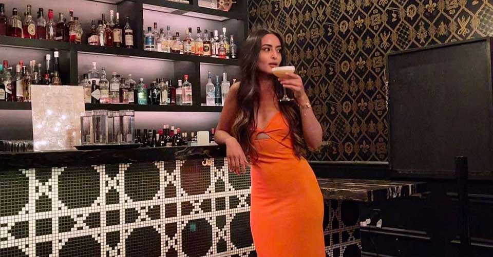 A woman in orange drinking at Novela