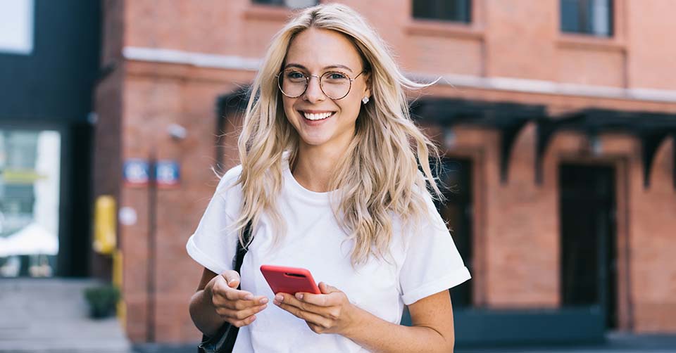 Woman in glasses using a dating app while walking