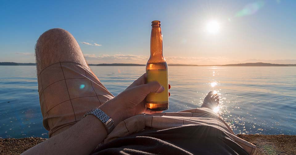 A man enjoying a beer by the sea
