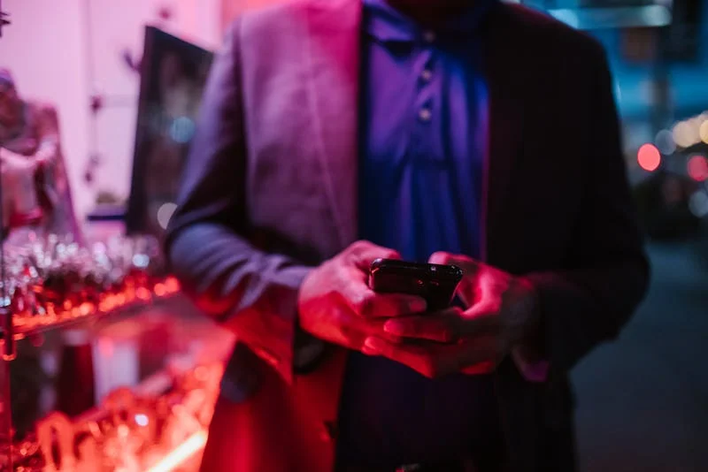 Man reviewing dating apps on a smartphone at night in a city