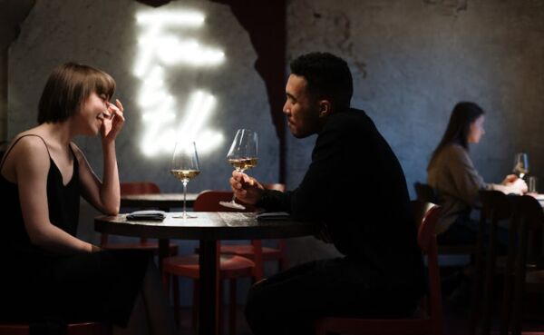 Young couple enjoying a casual date at a cozy urban bar with smartphones, showcasing modern dating in 2025.