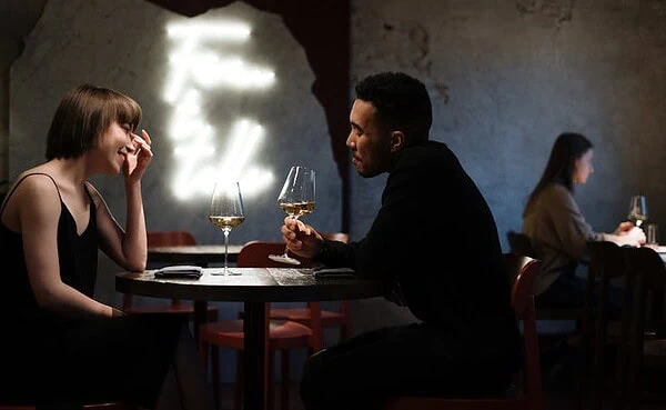 Young couple enjoying a casual date at a cozy urban bar with smartphones, showcasing modern dating in 2025.