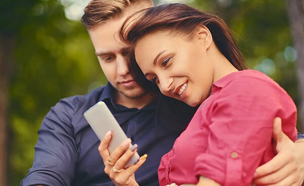 A couple on a date in a city park using smartphone and instant messaging.