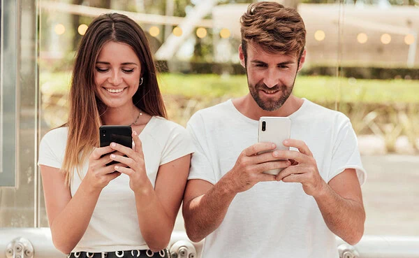 Adult Friend Finder vs Tinder 2025 comparison – two persons holding phones, they are side by side smiling