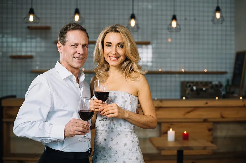 Mature couple in their 40s browsing dating app on smartphone at cafe